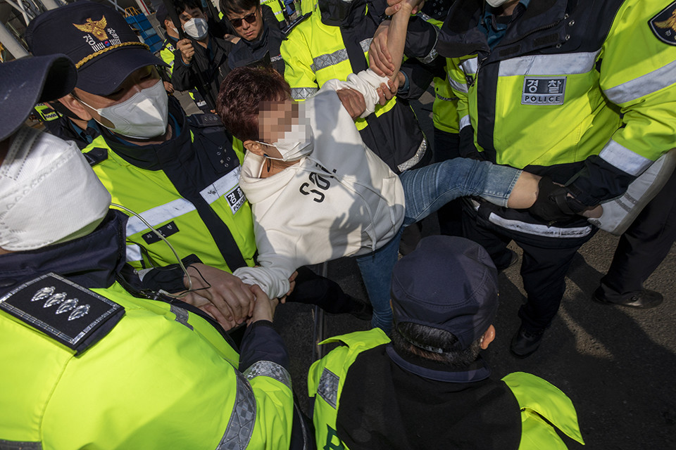 남성 경찰이 8일 금호석유화학 출입구 앞에서 한 여성의 사지를 들고 있다. ⓒ 노동과세계 정종배
