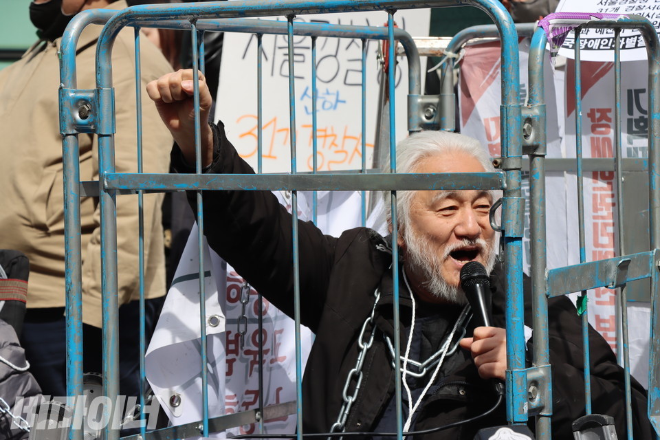 박경석 전국장애인차별철폐연대 상임공동대표가 철창 안에서 “투쟁”을 외치고 있다. (사진-비마이너)