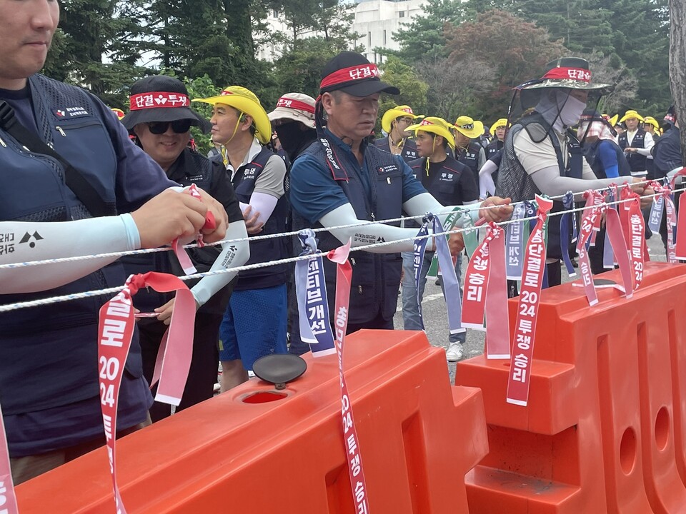 참가자들이 "총단결로 2024 투쟁 승리", "공정분배 쟁취", "인센티브 개선" 등이 적힌 리본을 매달고 있다.